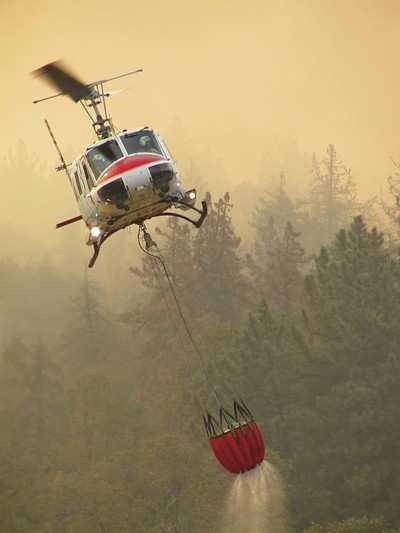 Hélicoptère bombardier d'eau larguant sur un feu de forêt